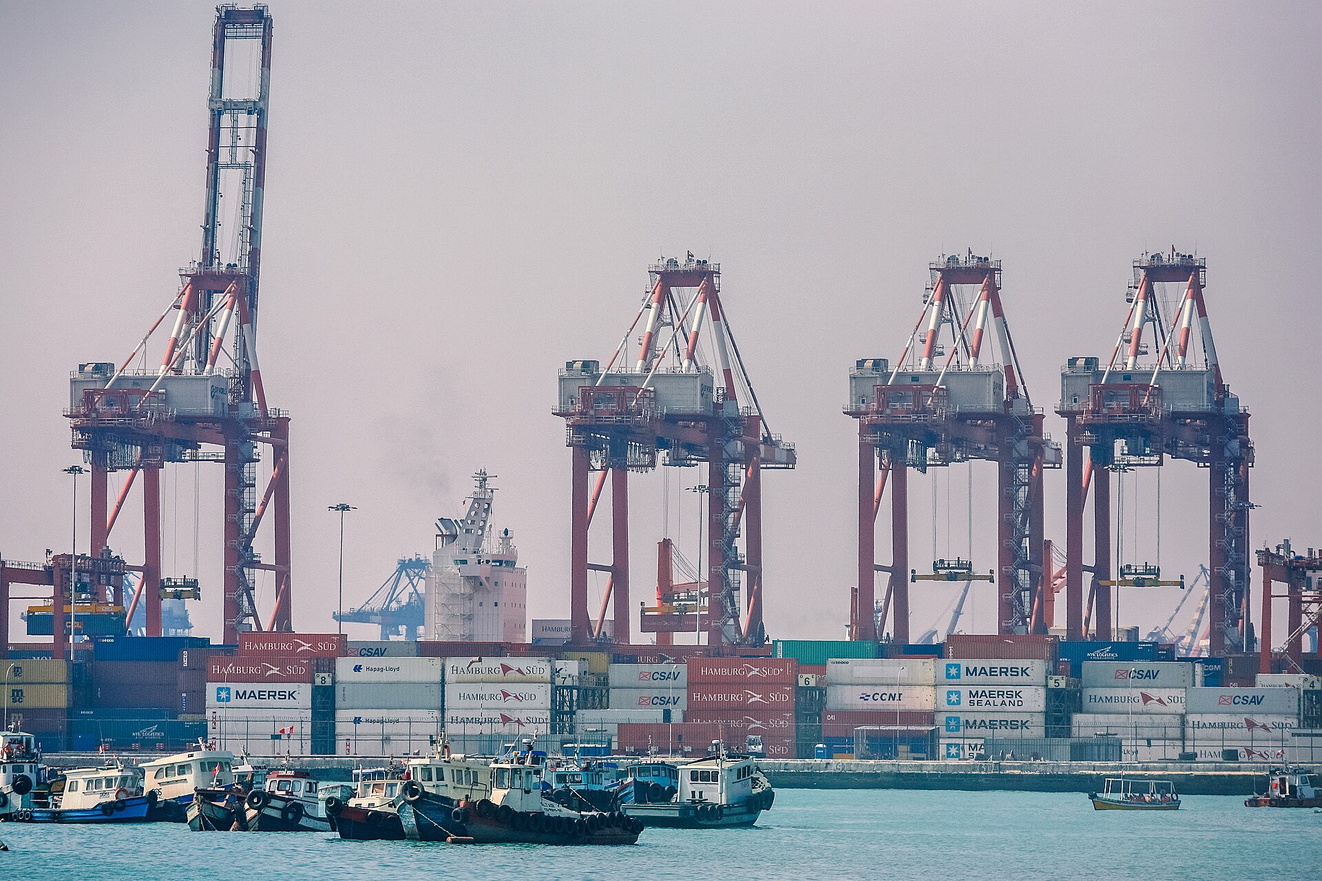 Container cranes and stacked containers at the port of Callao, Peru, with tugboats in the foreground
