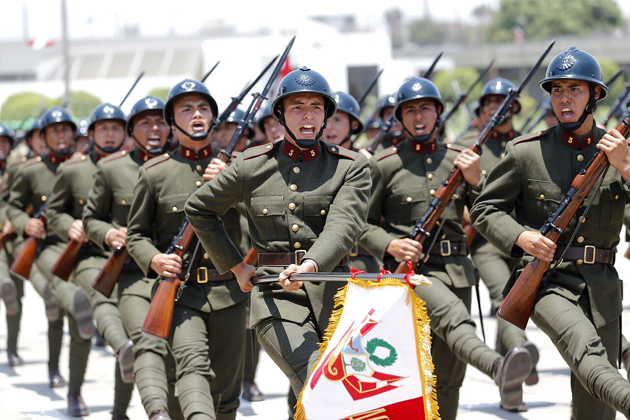Peruvian Army soldiers in historical uniforms marching with rifles and the Peruvian flag during a military parade