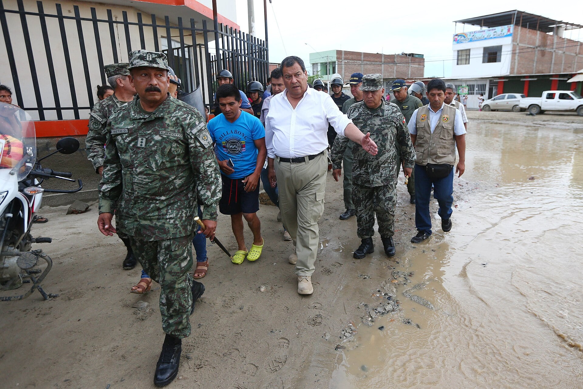 Officials and soldiers walk along a muddy flooded street in Piura, Peru, in March 2017
