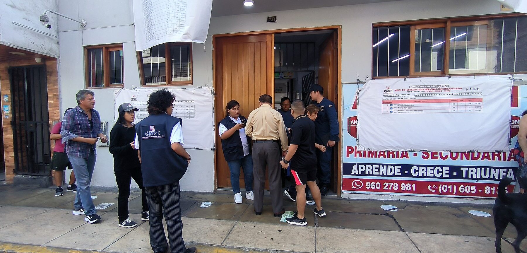 Voters and an ONPE official at the door of a school used as a polling station in Callao, Peru