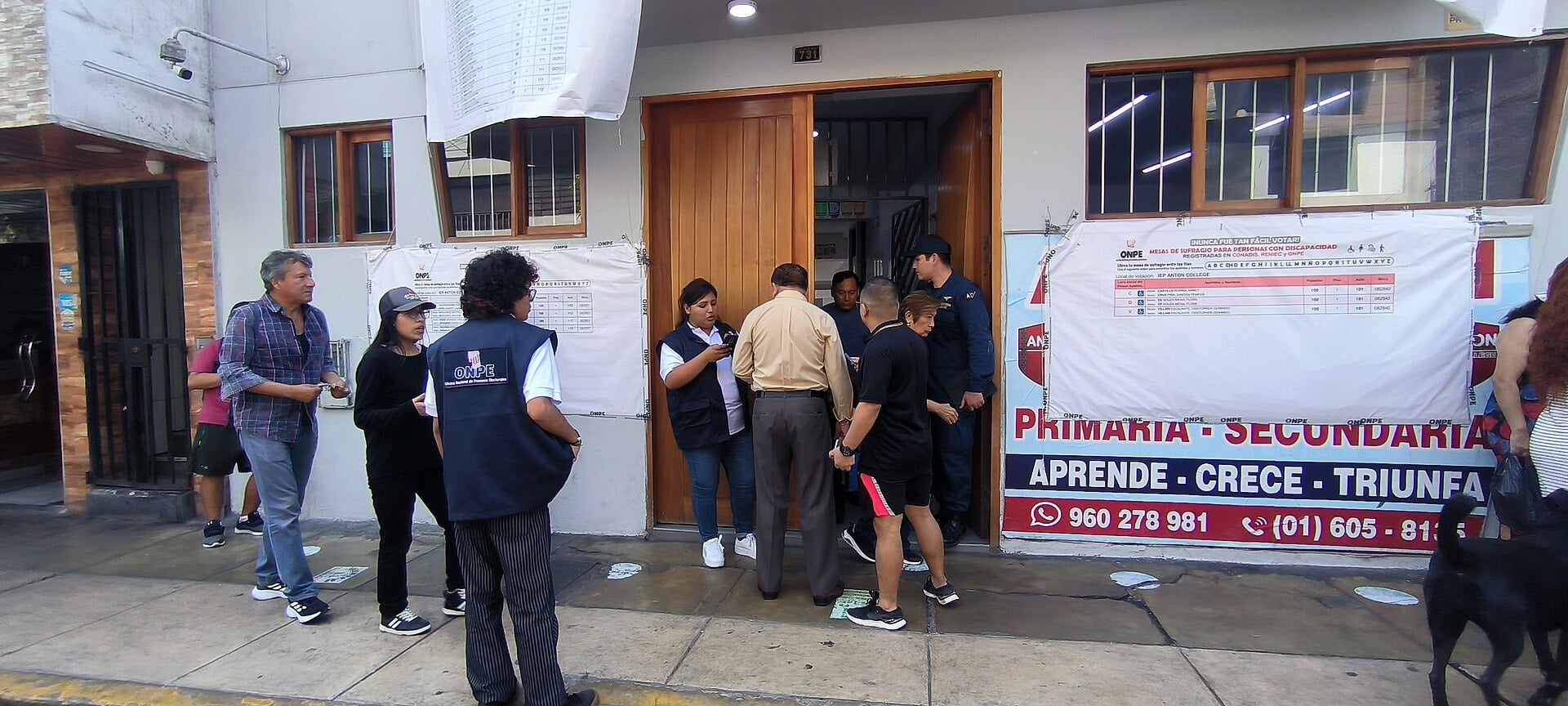 Voters and an ONPE official at the door of a school used as a polling station in Callao, Peru