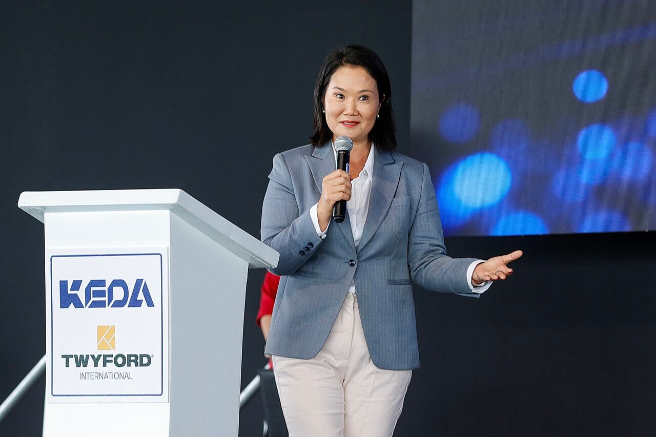 Peru's President Keiko Fujimori speaks into a microphone beside a white lectern at a public event