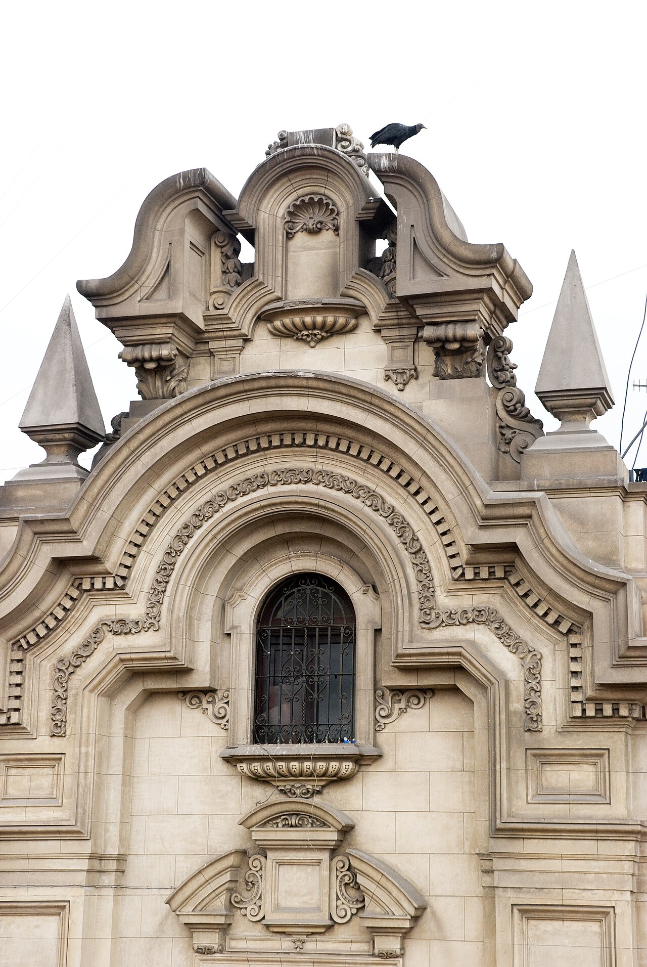Ornate stone facade of the Government Palace in Lima on Carabaya street, with a bird perched on the roofline