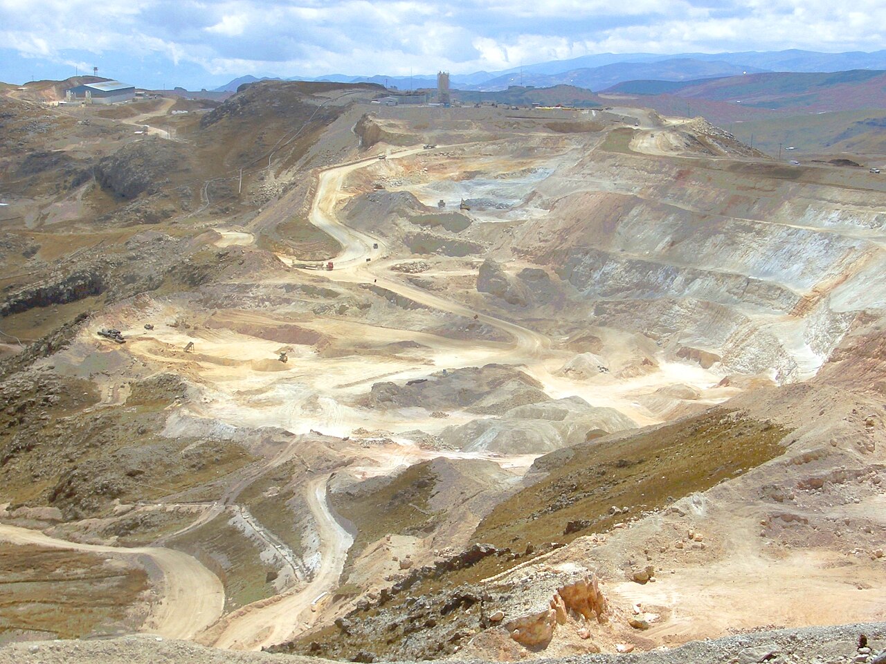 Terraced open-pit workings of the Yanacocha gold mine with haul roads and trucks in the dry highlands near Cajamarca in northern Peru