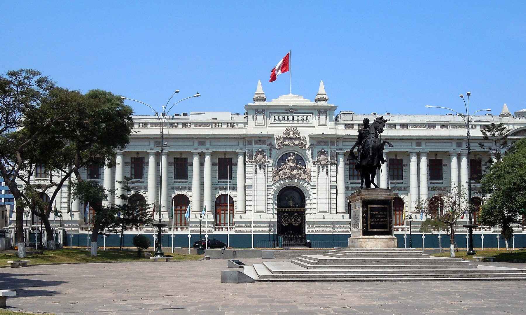 White neoclassical Legislative Palace of Peru’s Congress in Lima with the Congreso sign, a Peruvian flag and the equestrian statue of Simón Bolívar in front
