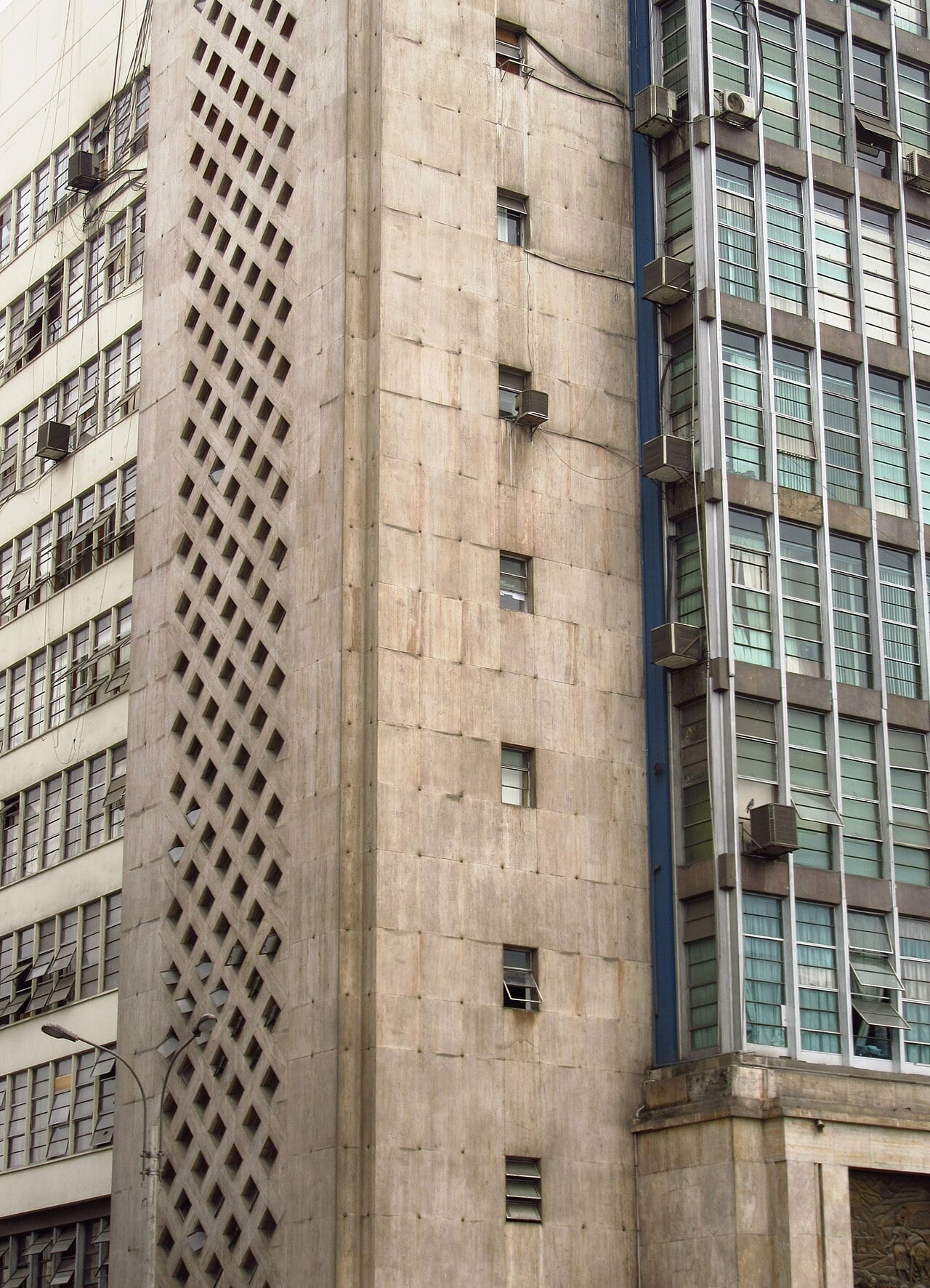 Concrete tower with a diagonal lattice pattern beside glass-fronted office floors at the Public Ministry headquarters in central Lima