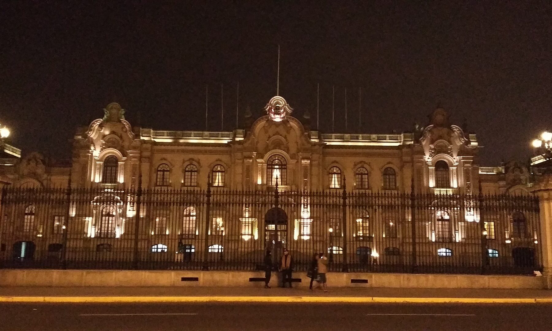 The Government Palace of Peru in Lima lit at night behind its iron fence