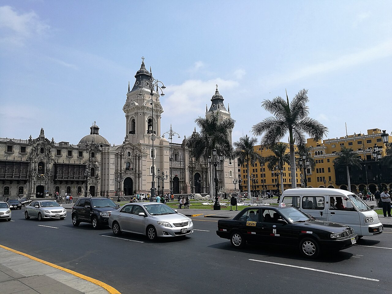 Lima Cathedral and the Archbishop's Palace on the Plaza Mayor, with palm trees and traffic in the foreground