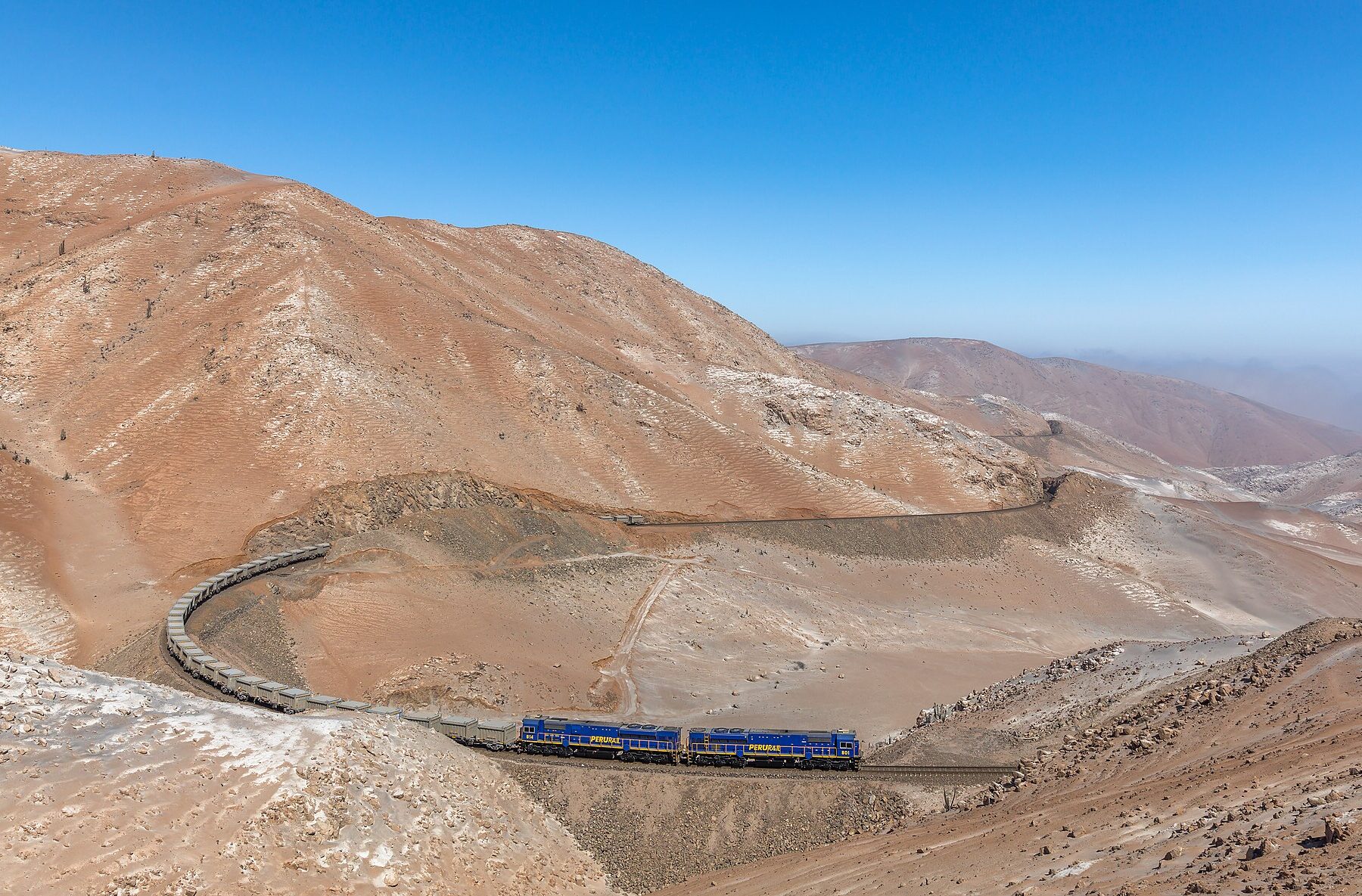PeruRail train hauling mineral cars through desert mountains between Matarani and La Joya, Peru