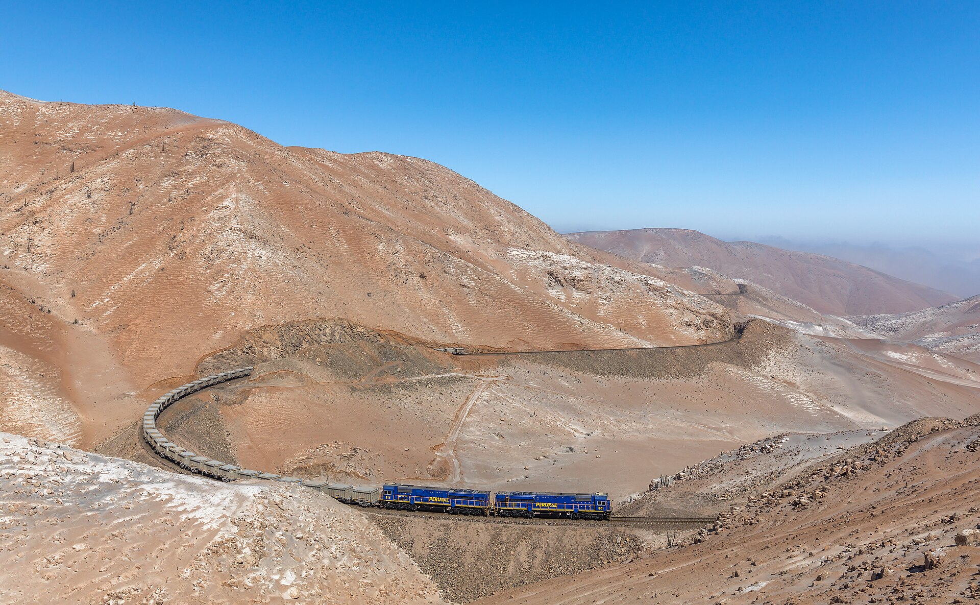 PeruRail train hauling mineral cars through desert mountains between Matarani and La Joya, Peru