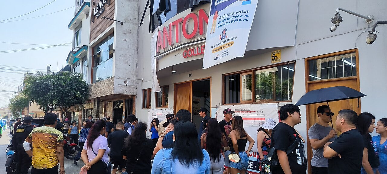 Voters queue outside a school polling station in Callao, Peru, under an ONPE banner listing voting hours of 7 a.m. to 5 p.m.