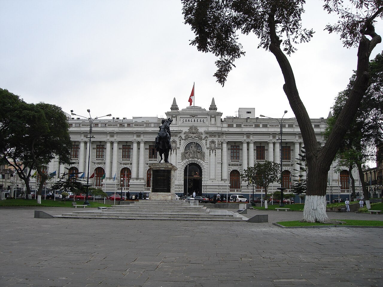 The white Congress building in Lima with a bronze equestrian statue in the plaza in front and a Peruvian flag on the roof