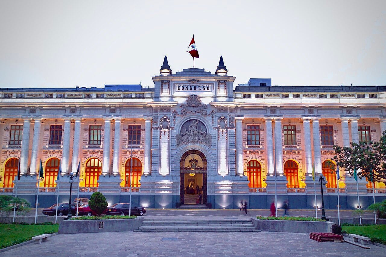 The lit facade of Peru's Legislative Palace in Lima, with the word Congreso above the entrance and the Peruvian flag on the roof