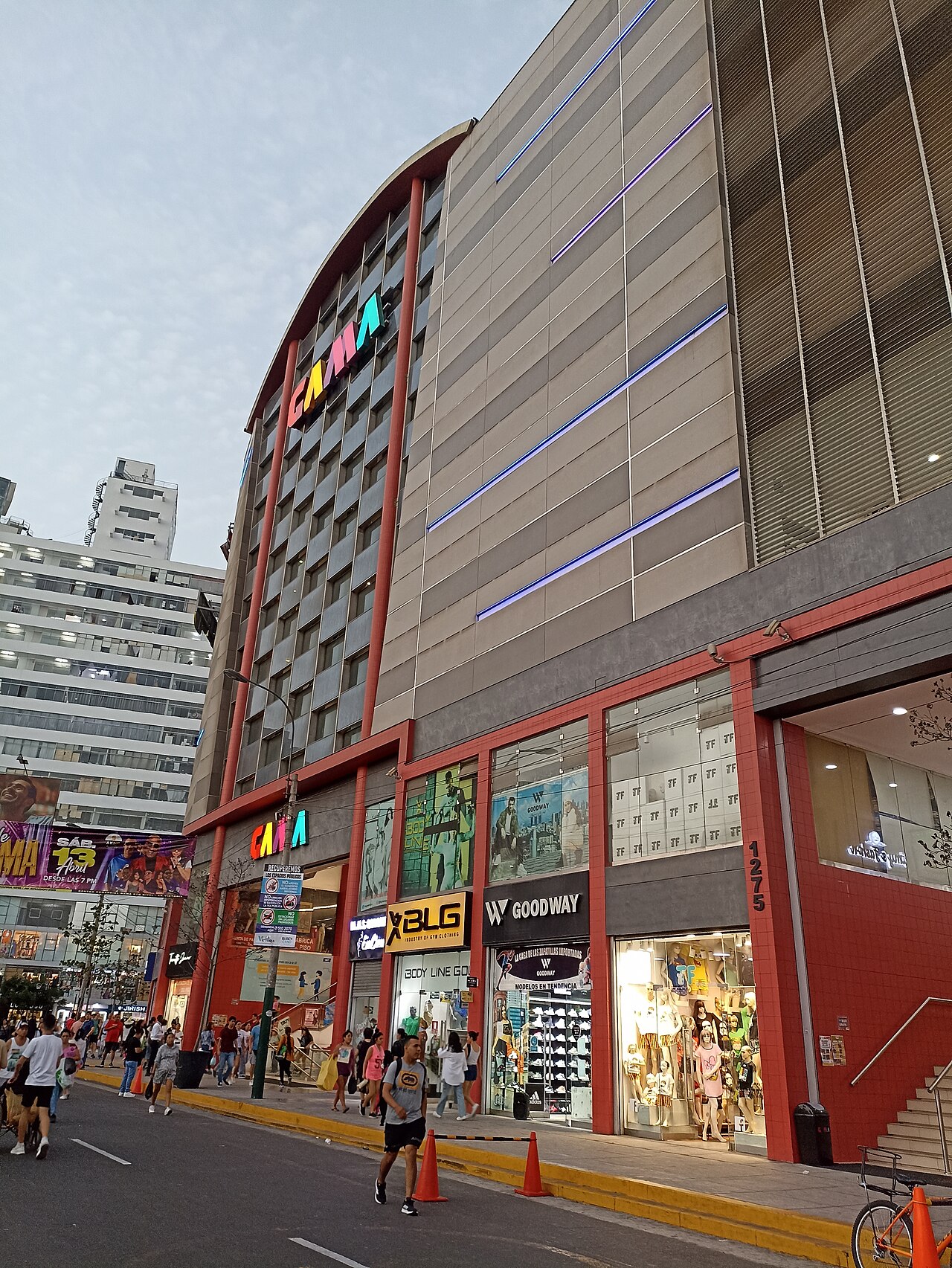 Garment shops at street level in a multi-story commercial building in Gamarra, Lima's clothing district, with shoppers on the street