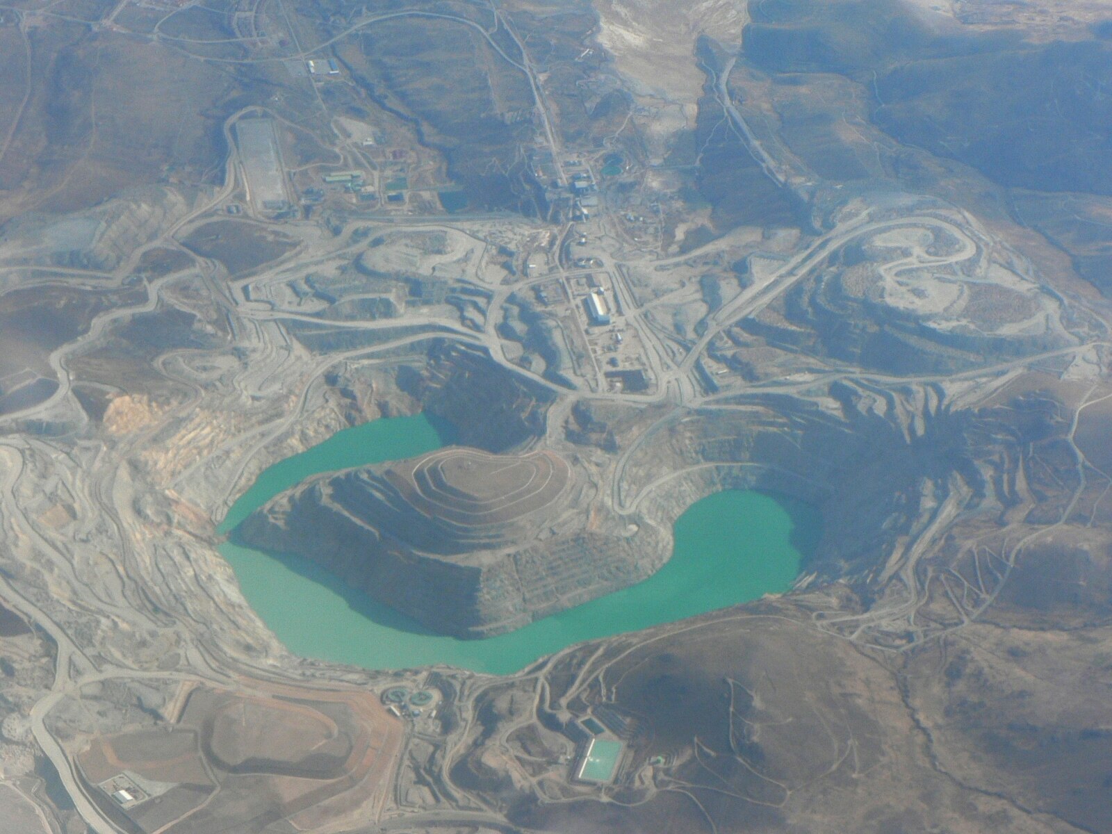 Aerial view of the Tintaya open-pit copper mine in Peru's Cusco region with a turquoise pit lake