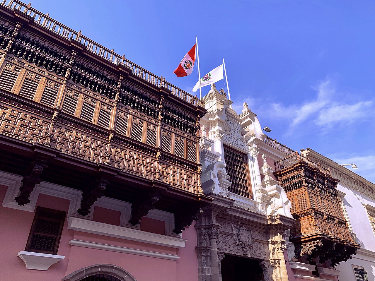 The carved wooden balconies of the pink Torre Tagle Palace in Lima, with the Peruvian flag flying above the entrance