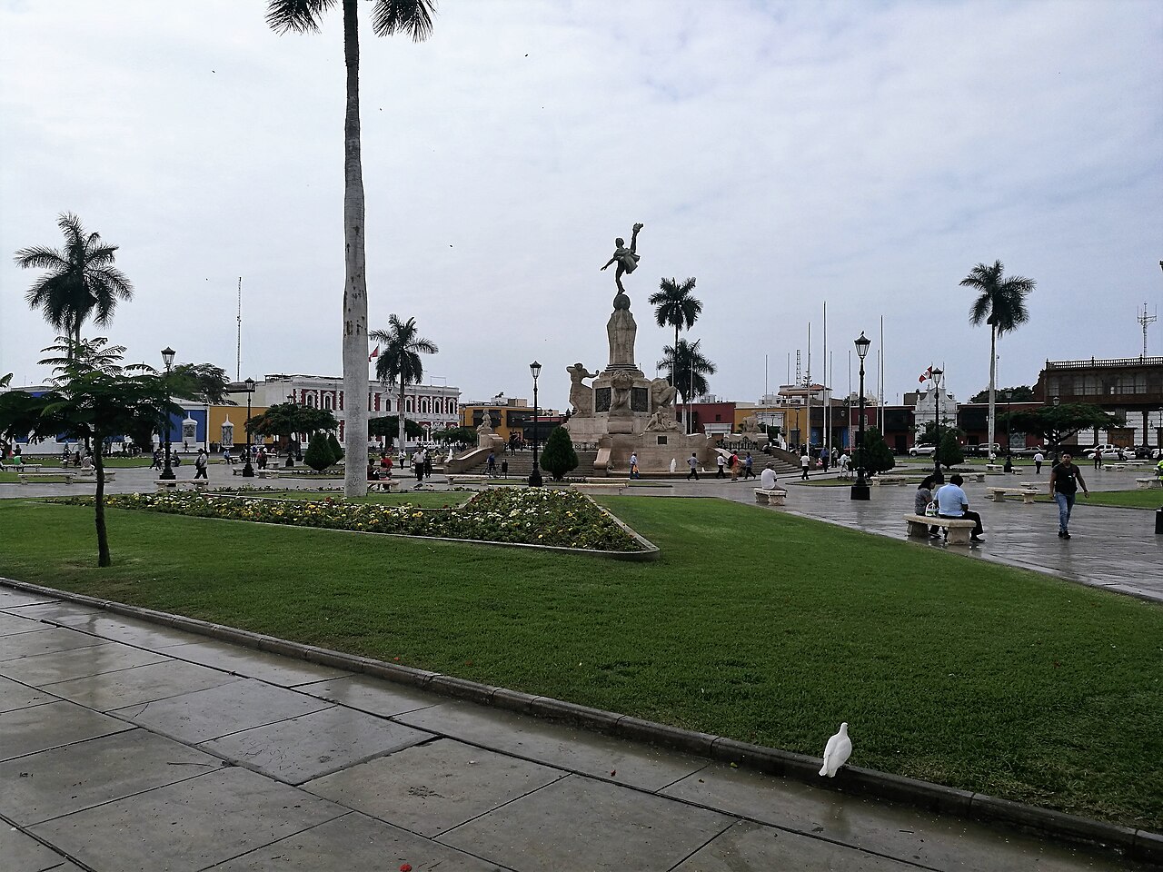 Palm trees, lawns and the Freedom Monument in the Plaza de Armas of Trujillo, Peru, on a cloudy day
