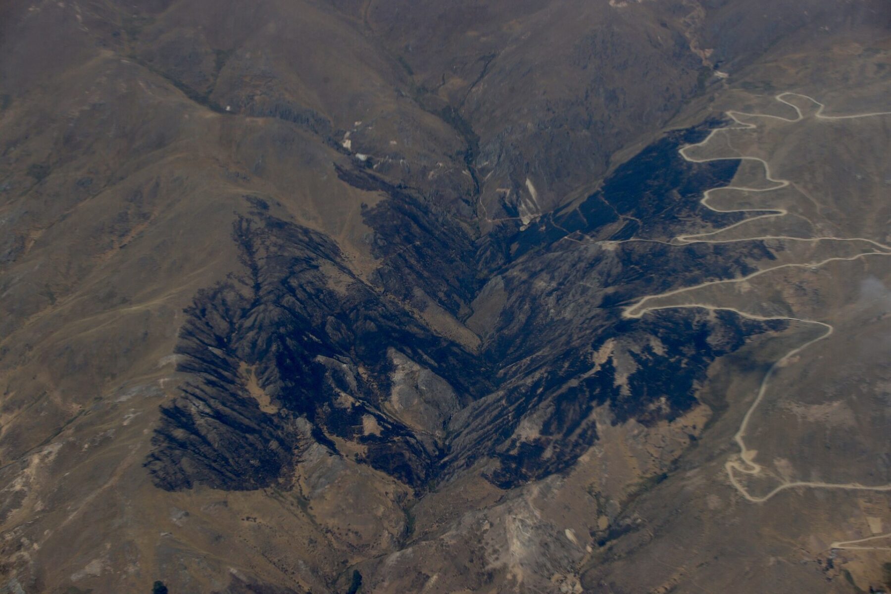Burned black slopes of an Andean valley in Peru seen from the air, a file photo of a wildfire scar in Áncash in September 2024, for Peru wildfires