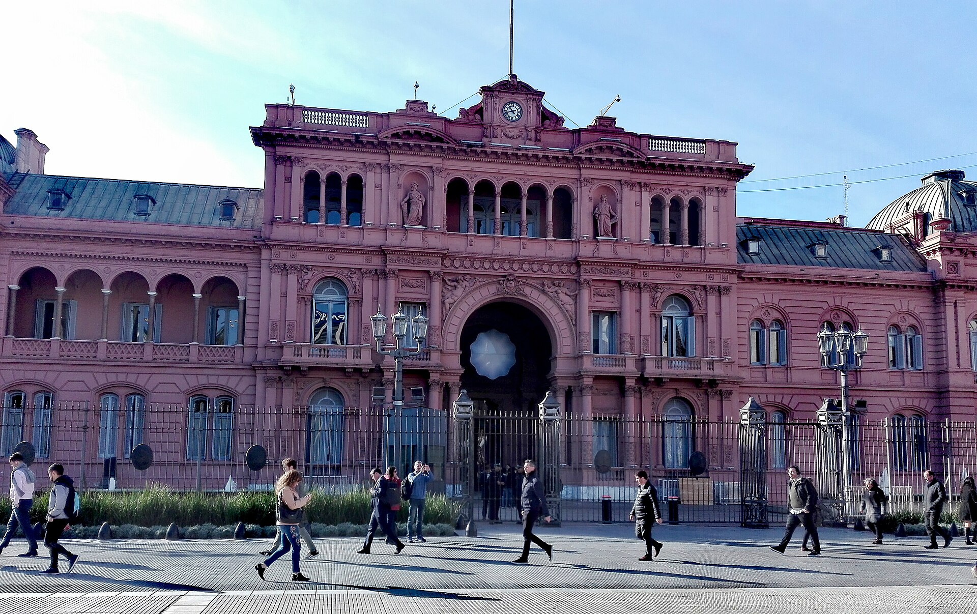The pink facade of the Casa Rosada presidential palace with pedestrians walking past on the square