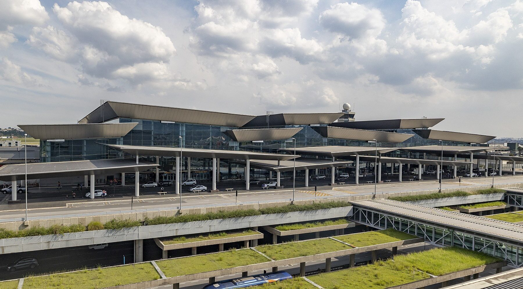 Exterior of Terminal 3 at Sao Paulo Guarulhos International Airport with curved roof canopies, glass facade and green roof gardens