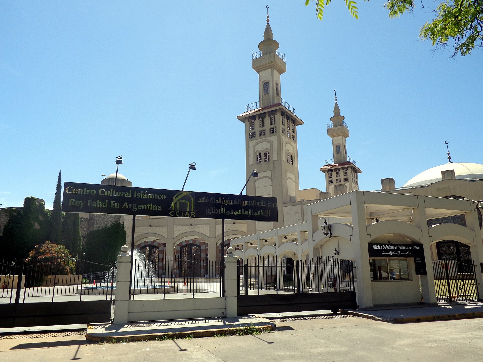 The entrance sign, minarets and white dome of the King Fahd Islamic Cultural Centre under a blue sky