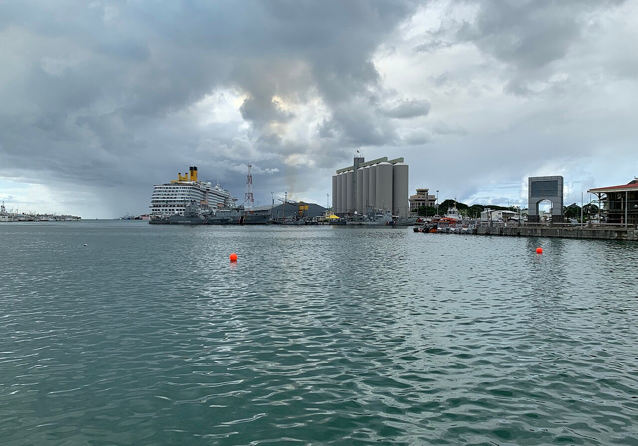 A cruise ship, coast guard vessels and grain silos in the harbour of Port Louis, Mauritius, under a cloudy sky