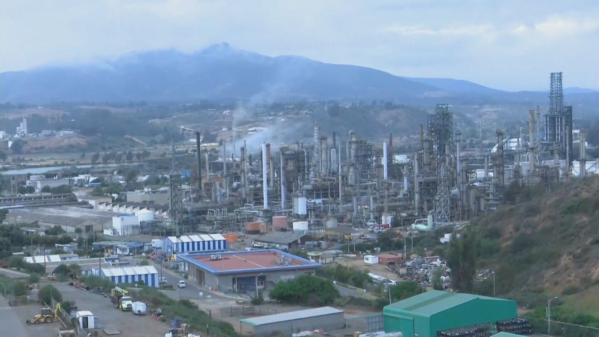 Wide view of the ENAP oil refinery in Concón with towers, chimneys and storage tanks below a mountain range