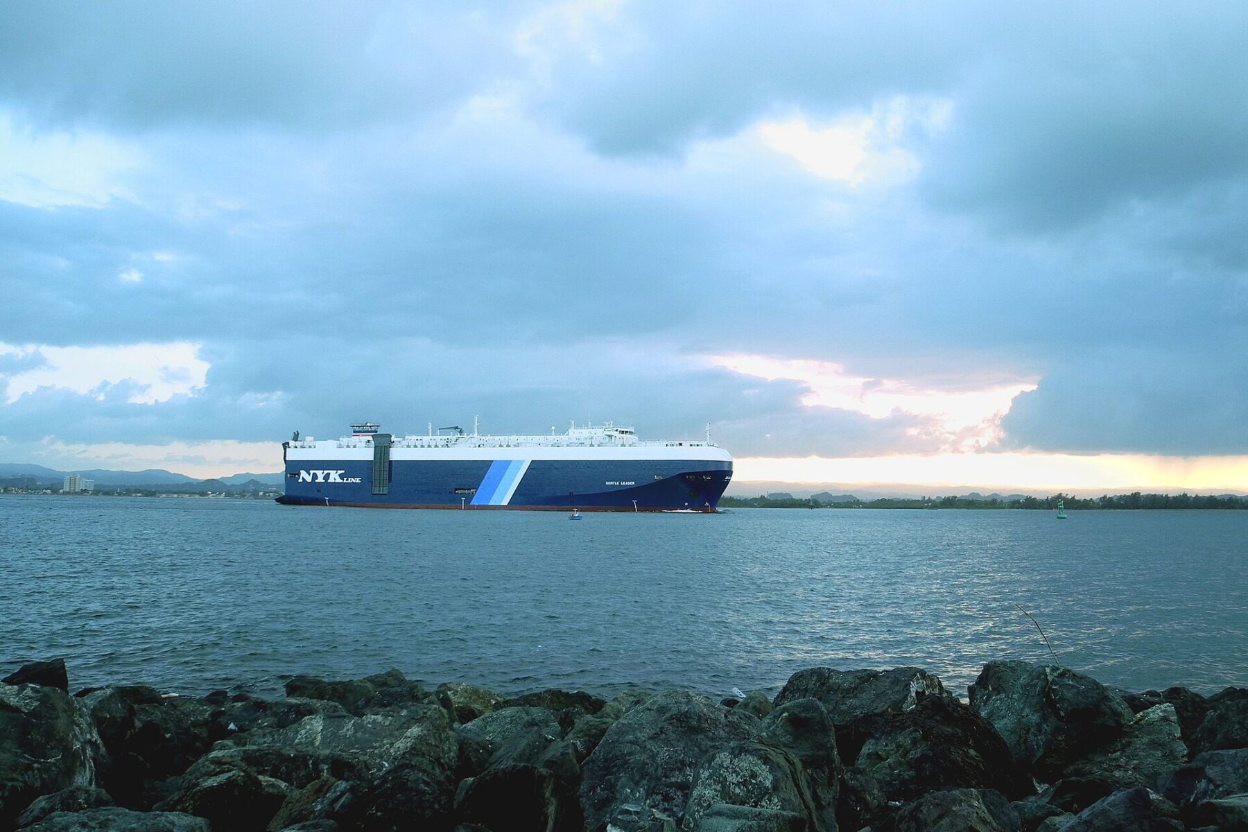 A large cargo ship entering San Juan Bay in Puerto Rico under a cloudy evening sky