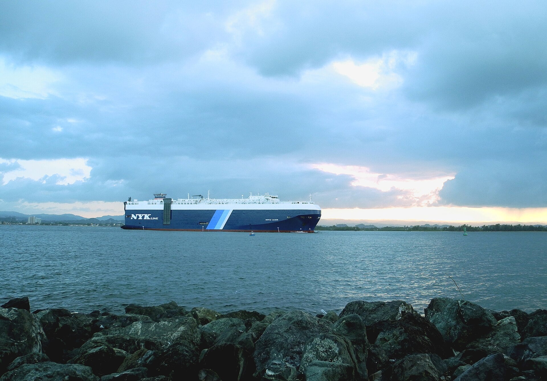A large cargo ship entering San Juan Bay in Puerto Rico under a cloudy evening sky