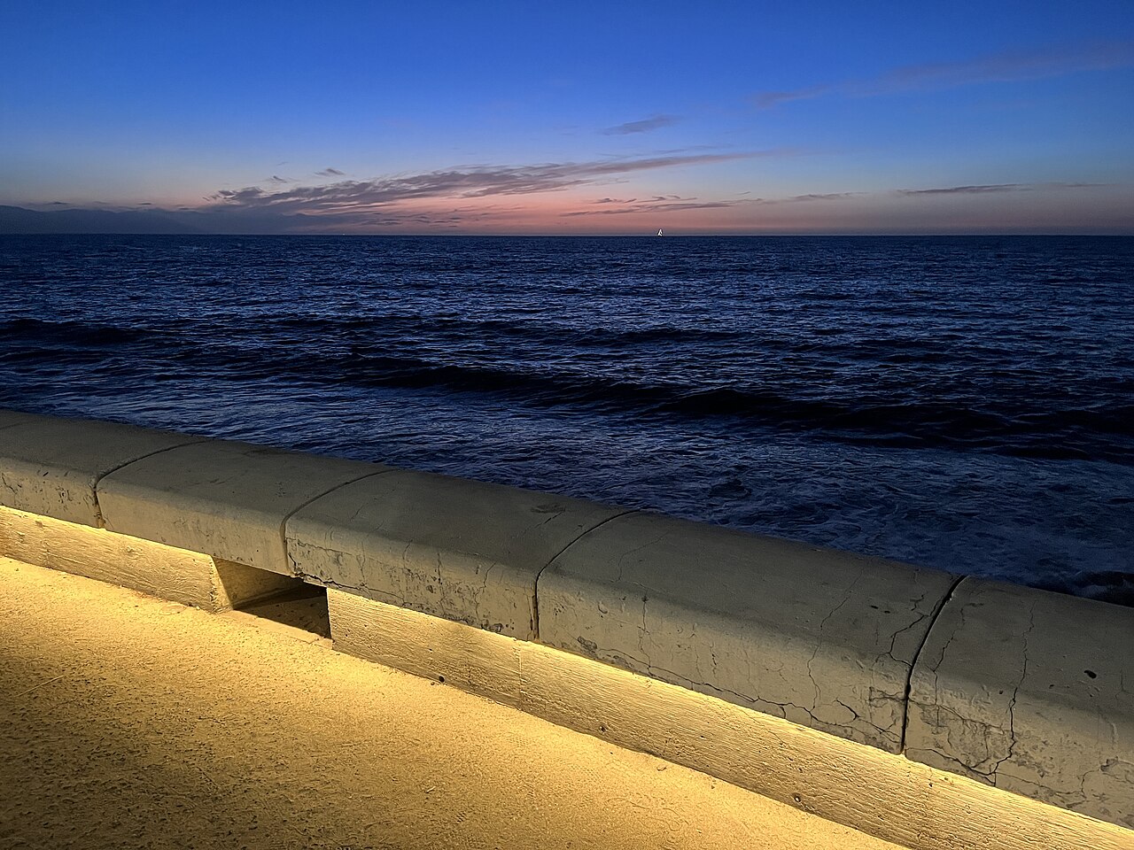 Waves on Banderas Bay beside the lit seawall of the Malecón promenade in Puerto Vallarta at dusk