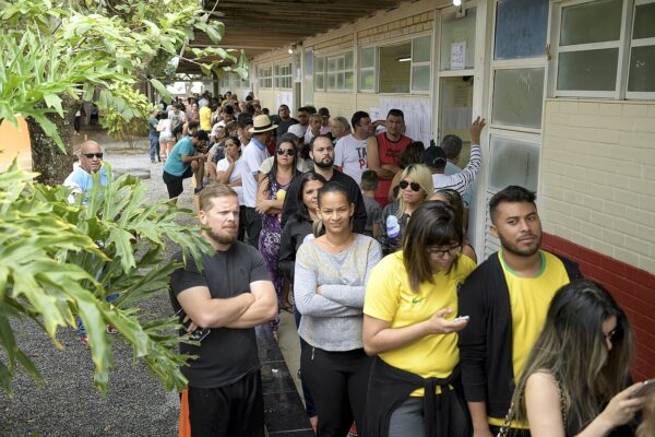 Voters stand in a long queue outside classrooms used as a polling station in Brazil
