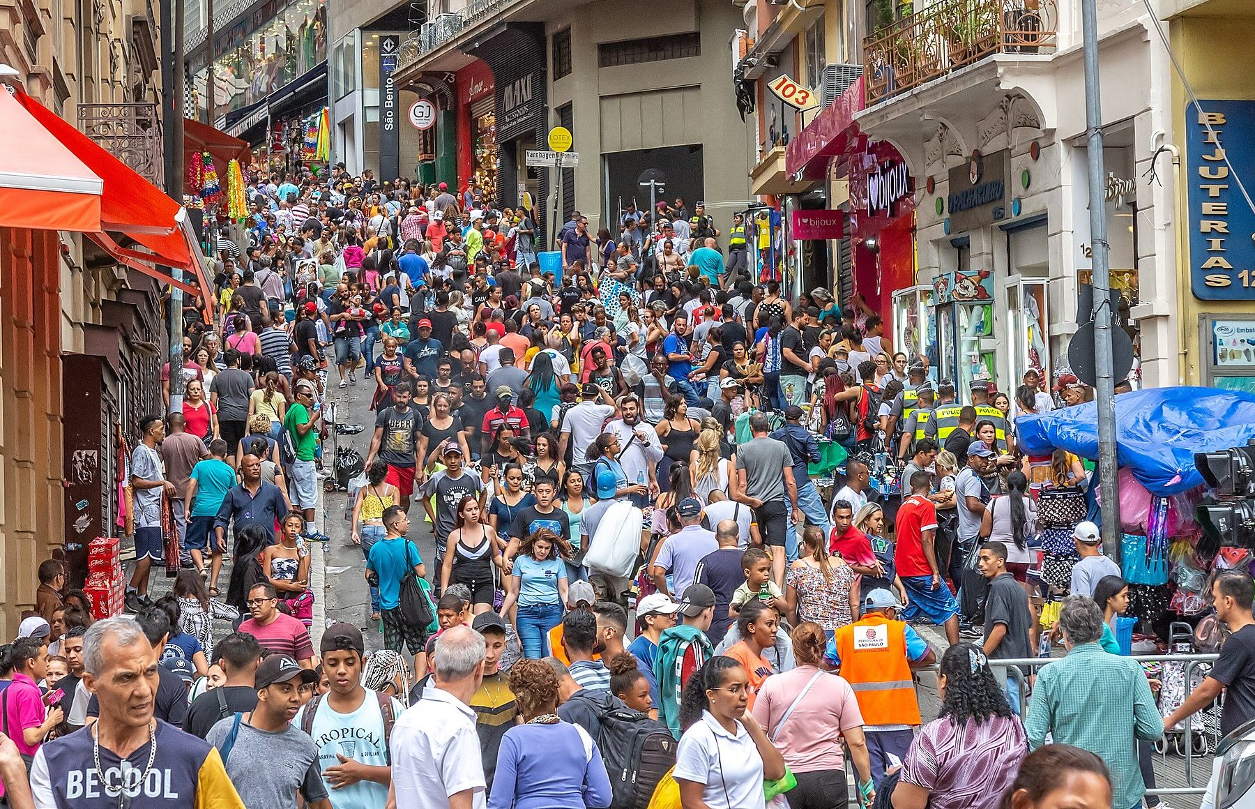 A dense crowd of shoppers walking down a narrow street lined with shops in downtown São Paulo