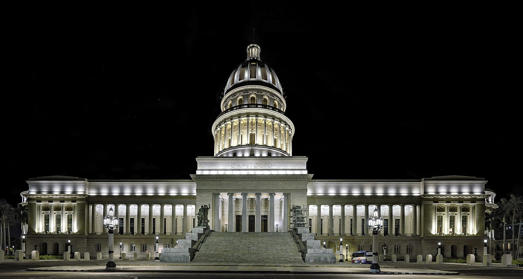 The floodlit Capitolio in Havana at night, with its central dome, a wide stairway and a lit colonnade on each side under a black sky