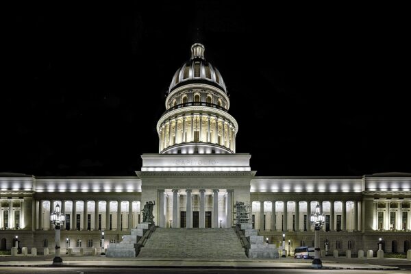 The floodlit Capitolio in Havana at night, with its central dome, a wide stairway and a lit colonnade on each side under a black sky