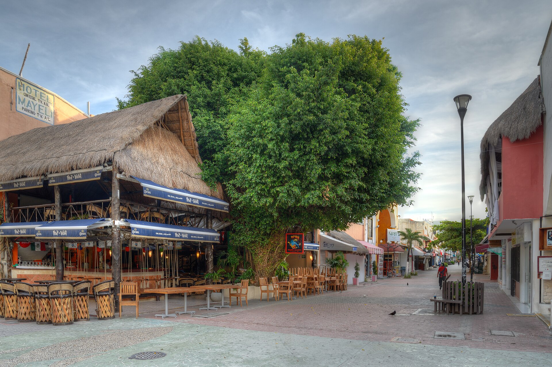 Pedestrian street lined with a thatched-roof restaurant and shops on Quinta Avenida in Playa del Carmen, Quintana Roo