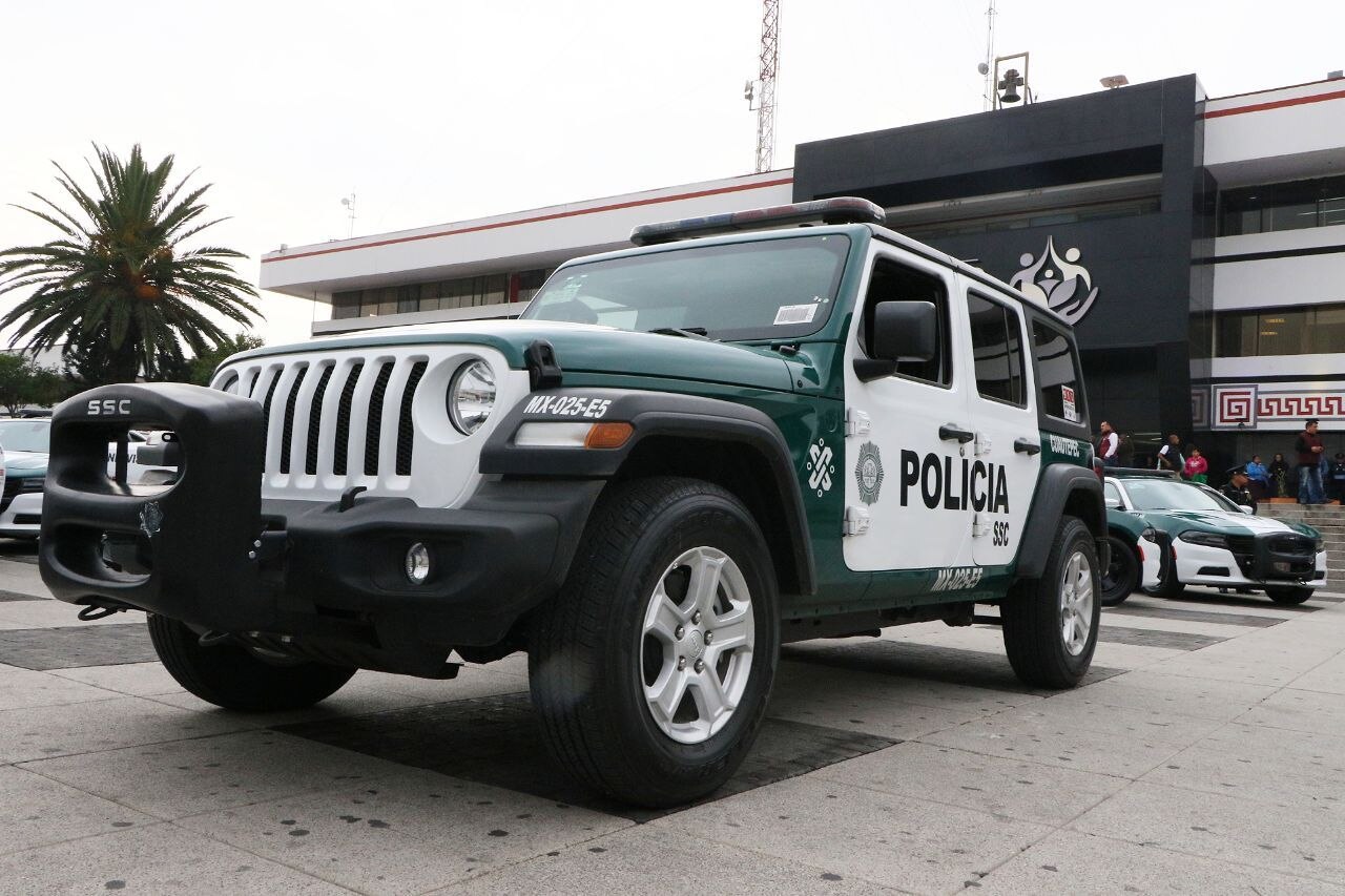 A green and white Mexico City police Jeep marked SSC and Policía parked in front of a government building