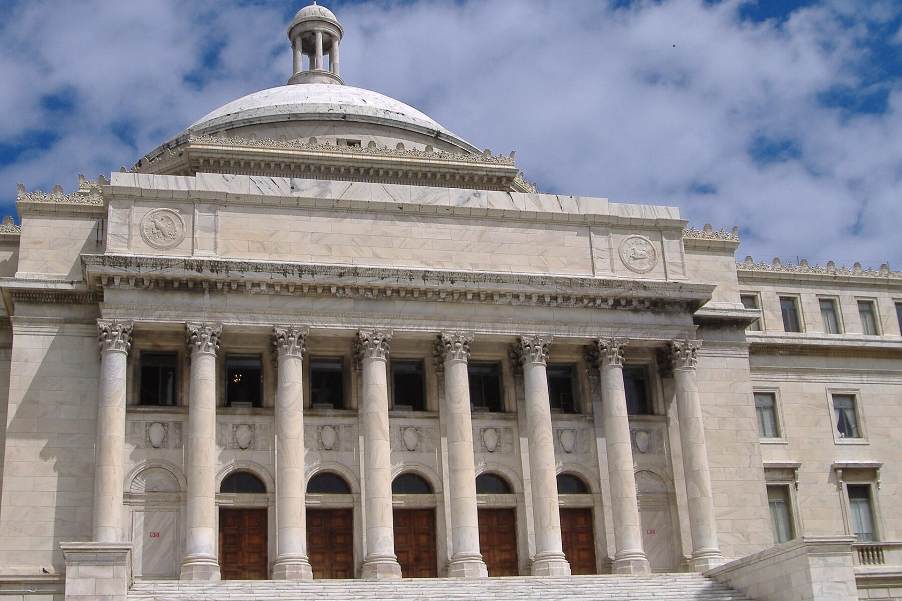 White marble Capitol of Puerto Rico in San Juan with its dome, columns and entrance steps under a cloudy blue sky