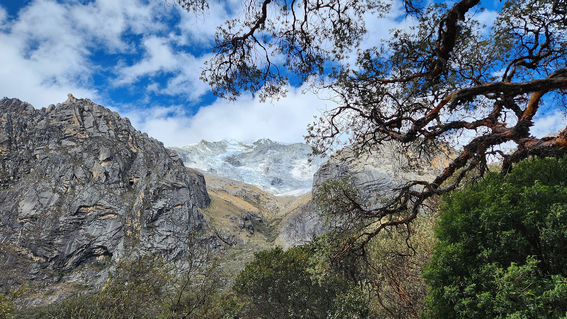 Glacier-covered Huascaran massif seen between rock walls and trees in the Llanganuco gorge