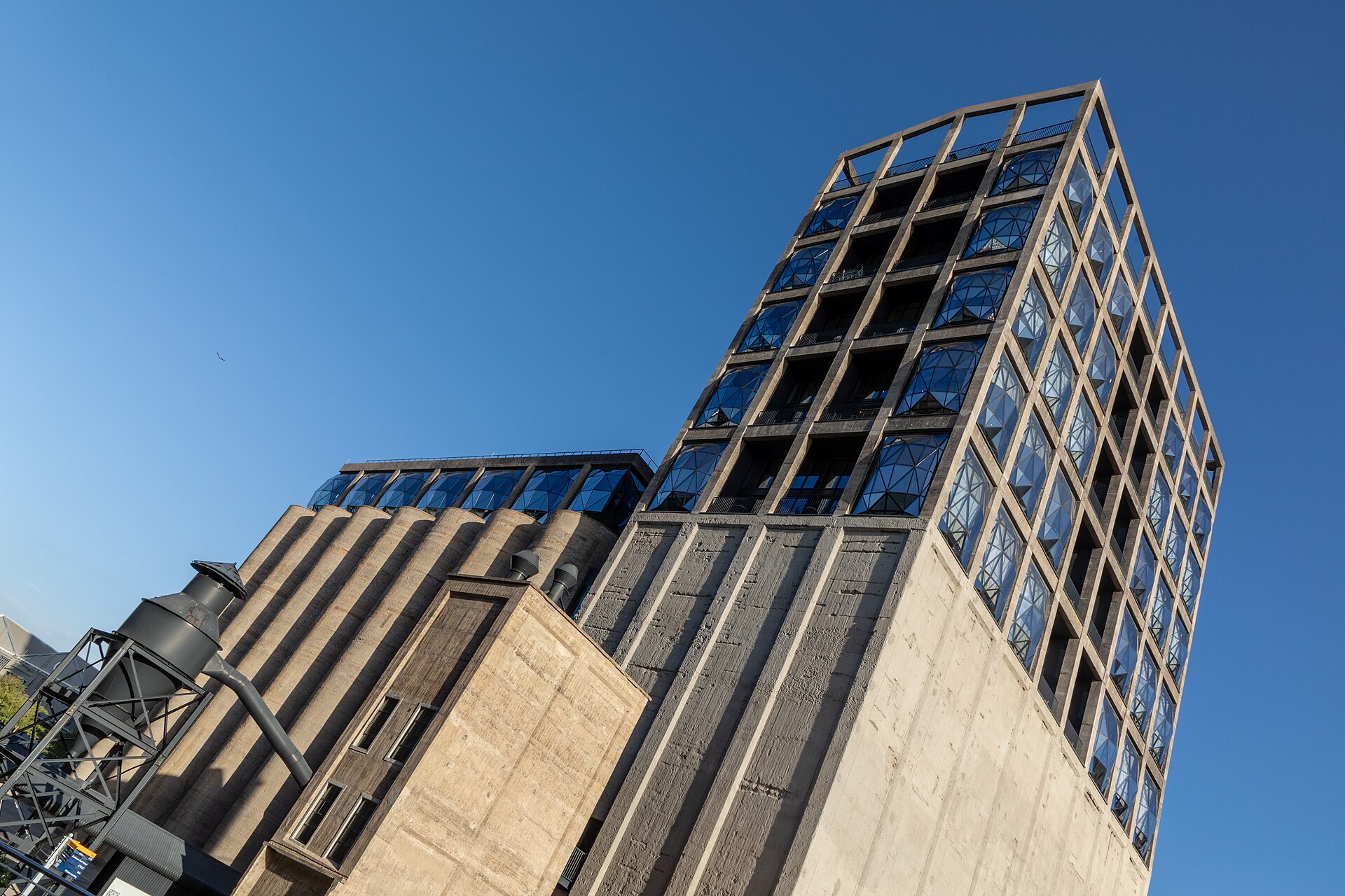 The concrete grain-silo tower of the Zeitz MOCAA museum with faceted glass windows against a clear blue sky
