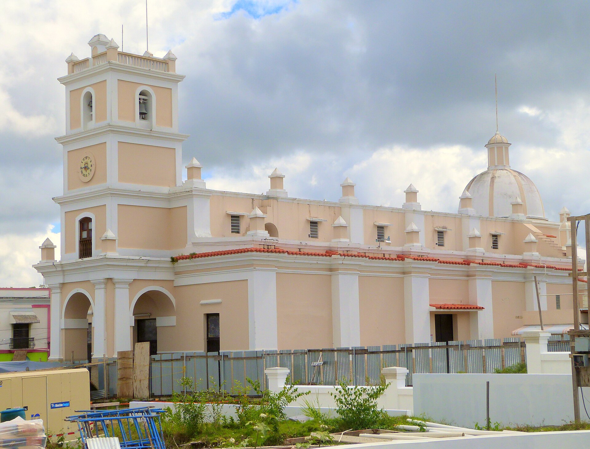 The cream and pale yellow Iglesia de Nuestra Senora de la Asuncion in Cayey, with a bell tower, a dome and a cloudy sky