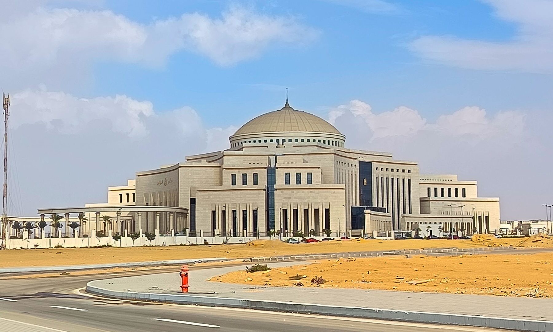 The domed, cream-coloured Egyptian parliament building in the New Administrative Capital, with an empty road and sand in the foreground