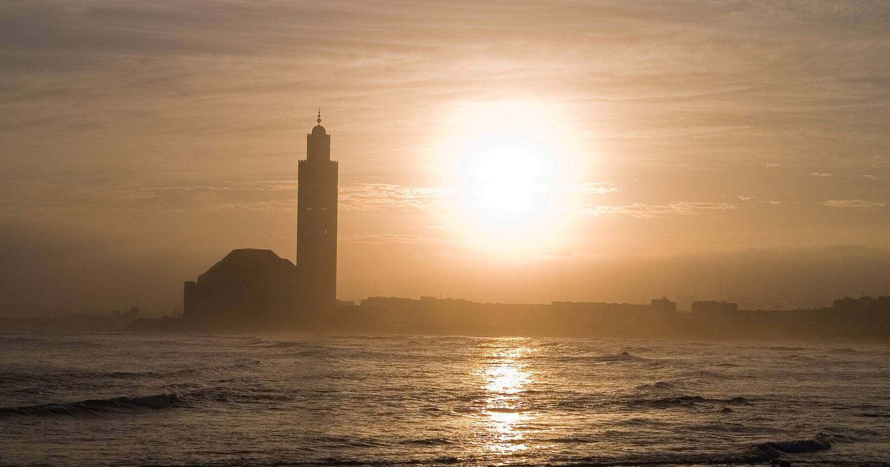 Silhouette of the Hassan II Mosque and its minaret in Casablanca against the rising sun over the Atlantic