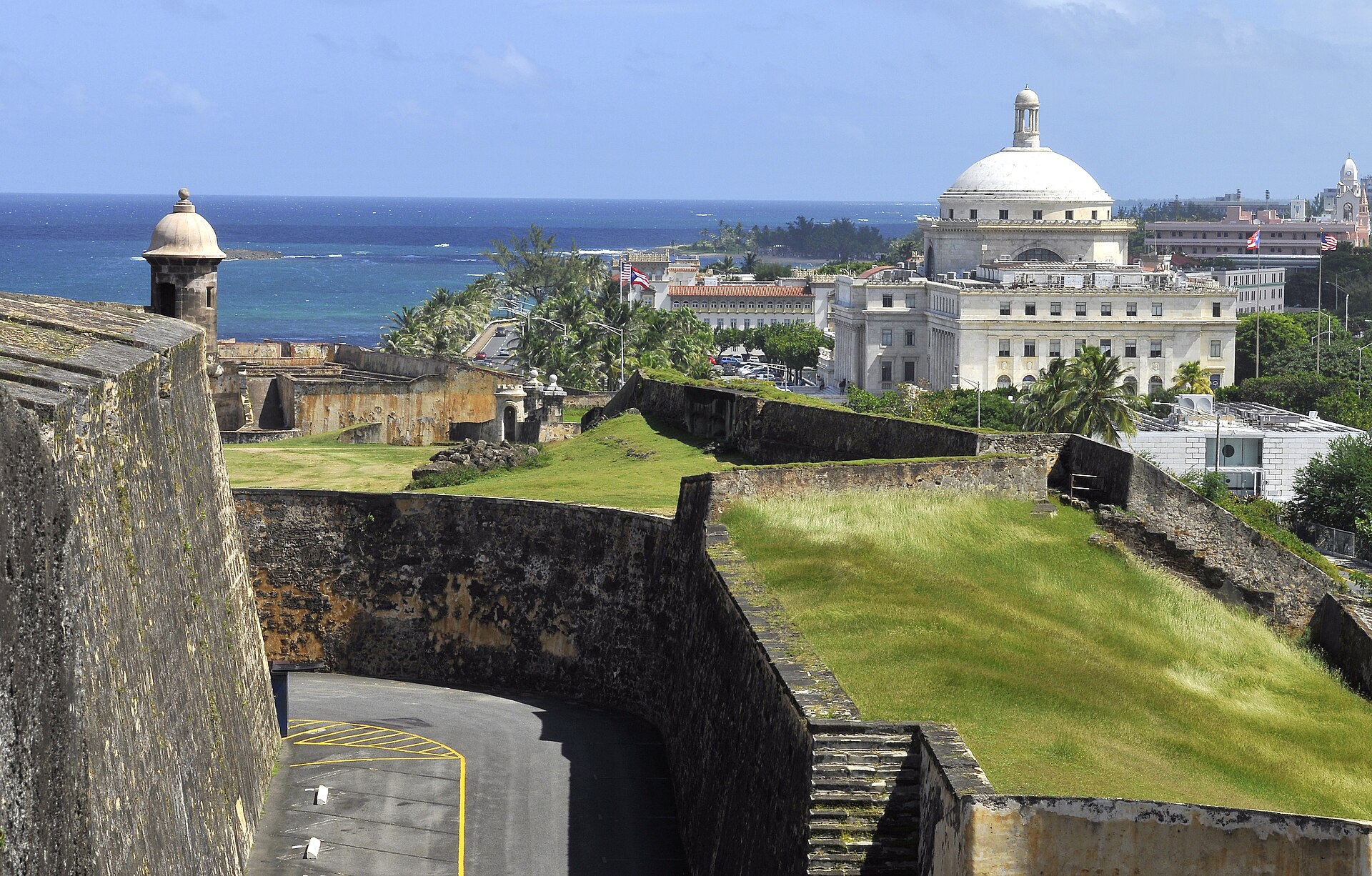Stone walls and green ramparts of the Castillo de San Cristobal in San Juan with the Capitol dome and the Atlantic in the background