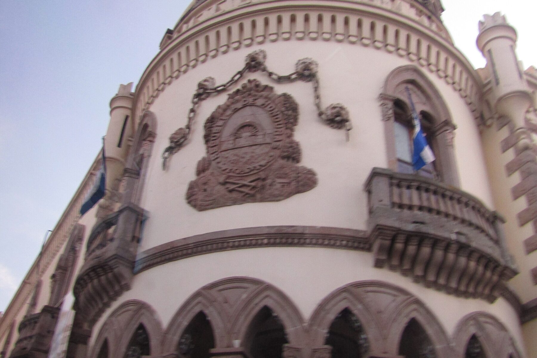 Curved facade of the former presidential palace in Tegucigalpa with the carved national coat of arms and Honduran flags