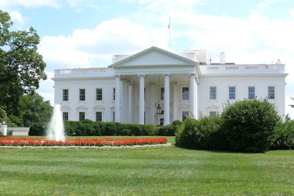 The north facade of the White House with its columned portico, fountain and lawn on a sunny day