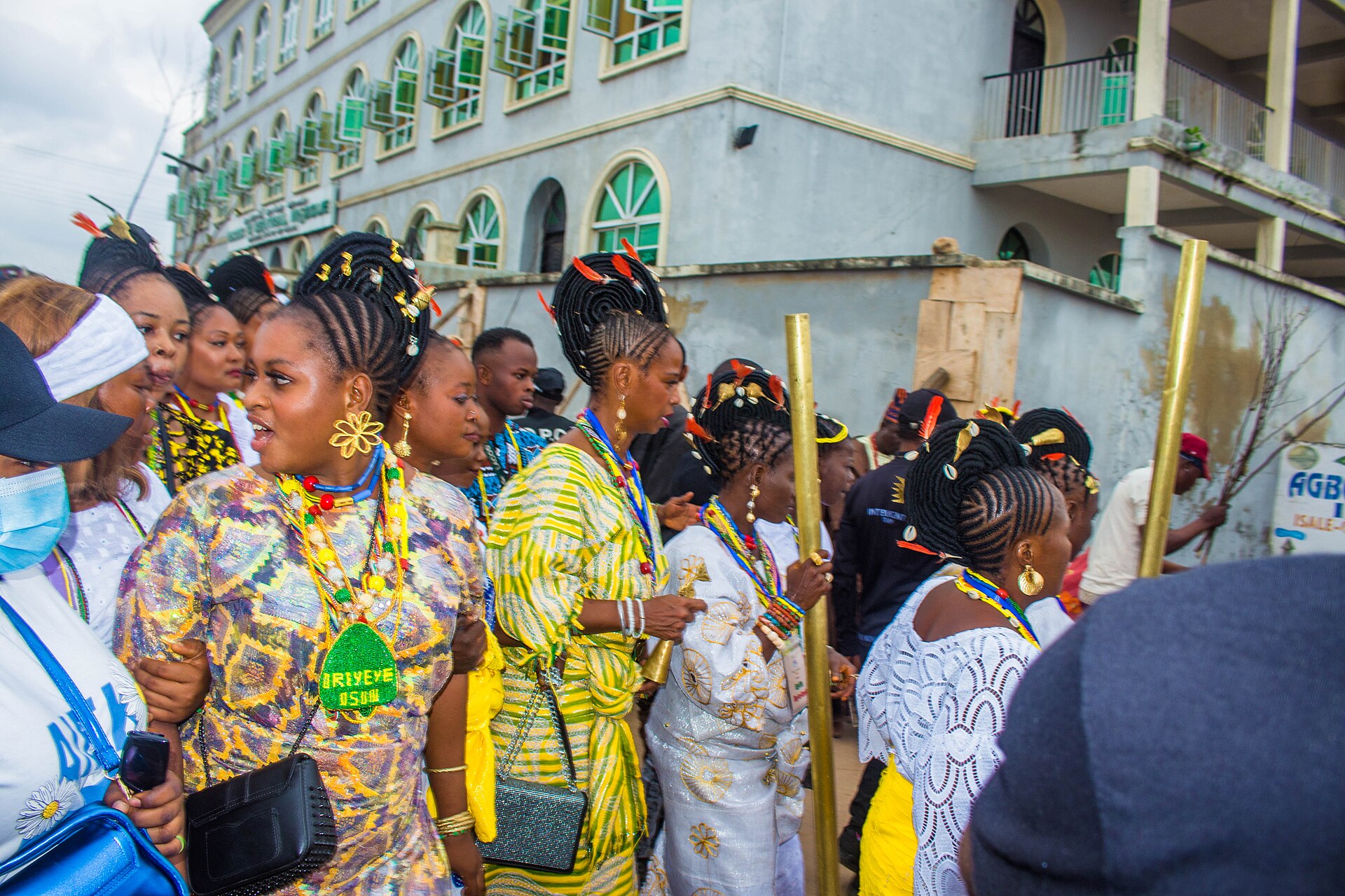 Yoruba women and men in colourful traditional dress and beaded jewellery walking in a crowd at the Osun Osogbo festival