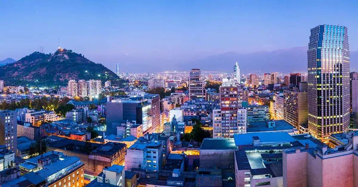 Santiago, Chile, at dusk with a lit hill and glass towers