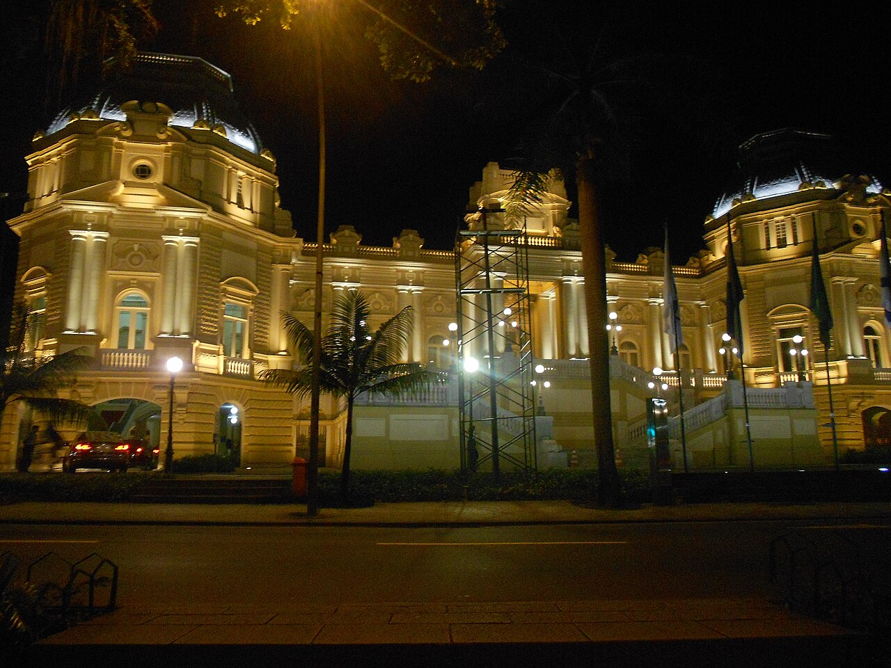 Palácio Guanabara lit up at night behind palm trees, with scaffolding in front, Rio de Janeiro