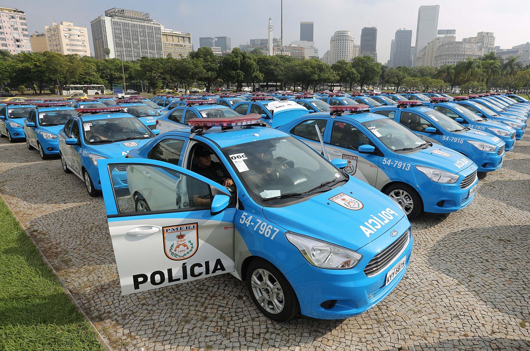 Rio de Janeiro Military Police patrol cars lined up in a park with the city skyline behind