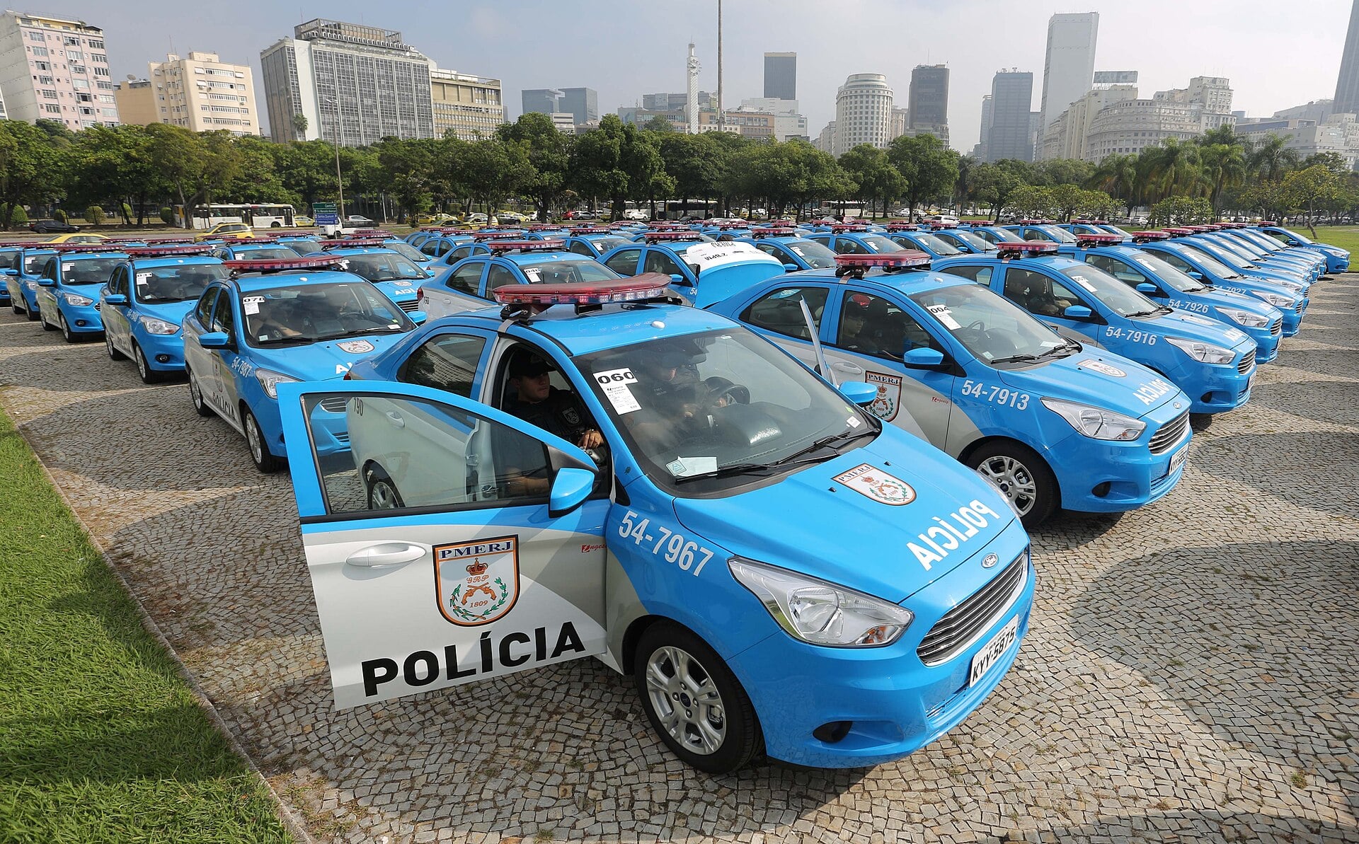 Rio de Janeiro Military Police patrol cars lined up in a park with the city skyline behind